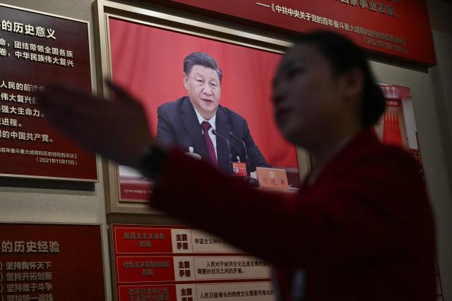 A woman walks past a portrait of China's President Xi Jinping at the Museum of the Communist Party of China in Beijing on March 1, 2026, ahead of the opening of the annual session of the National People's Congress (NPC). (Photo by Pedro PARDO / AFP)