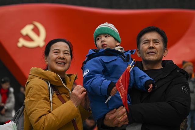 People watch a Chinese New Year performance of traditional Chinese dances with a sculptural flag of the Communist Party seen in the background at the plaza of the Museum of the Communist Party of China in Beijing on March 1, 2026, ahead of the opening of the annual session of the National People's Congress (NPC). (Photo by Pedro PARDO / AFP)