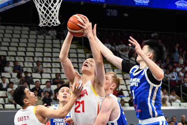 China's Hu Jinqiu (C) rebounds against Taiwan's Brandon Gilbeck (R) during the 2027 FIBA Basketball World Cup Asian qualifier first round group B match between China and Taiwan at the Mall of Asia Arena in Pasay city, Metro manila on March 1, 2026. (Photo by Ted ALJIBE / AFP)