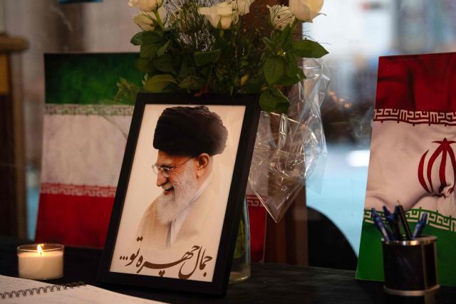 A portrait of Iran’s Supreme Leader Ayatollah Ali Khamenei is displayed next to Iranian flags, candles and a book of condolences at the Ahlul Bait Mosque Complex, while Muslim worshippers pray in his memory in Cape Town on March 01, 2026. Ayatollah Ali Khamenei, Iran's supreme leader since 1989 and sworn enemy of the West, was killed in the opening salvo of a massive US and Israeli attack, sparking a new wave of retaliatory missile strikes from Tehran on March 1, 2026. (Photo by RODGER BOSCH / AFP)