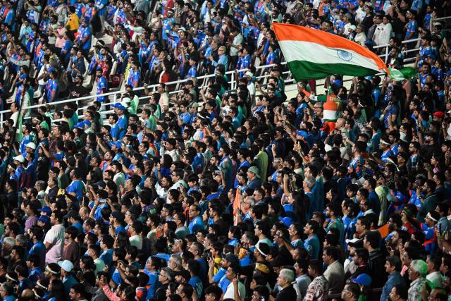 Fans wave India's national flag before the start of the 2026 ICC Men's T20 Cricket World Cup Super Eights match between India and West Indies at the Eden Gardens in Kolkata on March 1, 2026. (Photo by Dibyangshu SARKAR / AFP)