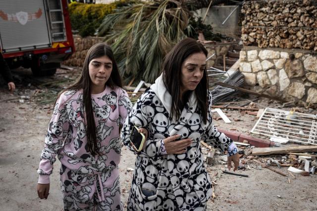 A mother and daughter leave the scene of a missile attack on Bet Shemesh, some 30 kilometres west of Jerusalem on March 1, 2026. A barrage of missiles launched from Iran killed at least six people in the central Israel city of Bet Shemesh on March 1, Israel's first responders agency, Magen David Adom (MDA) said, the day after the US and Israel attacked Iran and assassinated its supreme leader. (Photo by JOHN WESSELS / AFP)