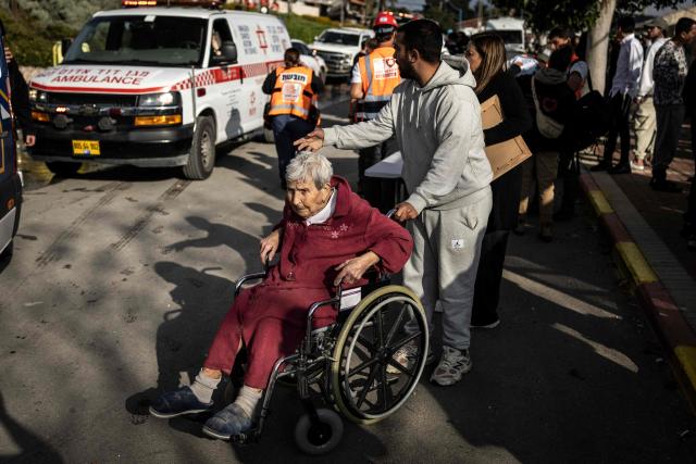 A woman is helped to leave the scene of a missile attack in Bet Shemesh, some 30 kilometres west of Jerusalem on March 1, 2026. A barrage of missiles launched from Iran killed at least six people in the central Israel city of Bet Shemesh on March 1, Israel's first responders agency, Magen David Adom (MDA) said, the day after the US and Israel attacked Iran and assassinated its supreme leader. (Photo by JOHN WESSELS / AFP)