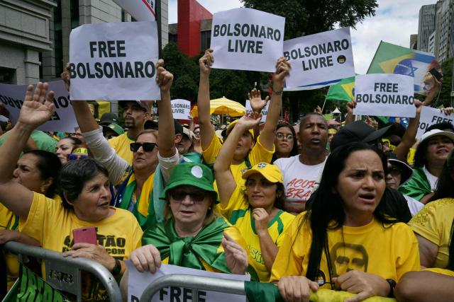 Supporters of former Brazilian president Jair Bolsonaro (2019-2022)—sentenced to 23 years and 3 months for attempted coup—hold signs that read in Portuguese, "Free Bolsonaro," as they take part in a demonstration in Sao Paulo, Brazil, on March 1, 2026. (Photo by NELSON ALMEIDA / AFP)