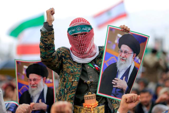 A masked man holds a picture of Iran's supreme leader Ali Khamenei during a memorial rally held by supporters of Yemen's Huthis, a day after Khamenei was assassinated during US and Israeli strikes on Tehran, in the Huthi-held capital Sanaa on March 1, 2026. The United States and Israel launched strikes against Iran on February 28, killing Iran's supreme leader and top military leaders, prompting authorities to retaliate with strikes on Israel and US bases across the Gulf. (Photo by Mohammed HUWAIS / AFP)