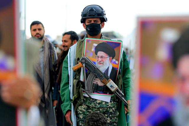 A masked man stands with a picture of Iran's supreme leader Ali Khamenei during a memorial rally held by supporters of Yemen's Huthis, a day after Khamenei was assassinated during US and Israeli strikes on Tehran, in the Huthi-held capital Sanaa on March 1, 2026. The United States and Israel launched strikes against Iran on February 28, killing Iran's supreme leader and top military leaders, prompting authorities to retaliate with strikes on Israel and US bases across the Gulf. (Photo by Mohammed HUWAIS / AFP)
