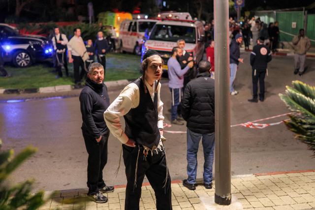 People gather near ambulances and first responders outside a building where an accidental fire was reported in Tel Aviv on March 1, 2026. The United States and Israel launched strikes against Iran on February 28, killing Iran's supreme leader and top military leaders, prompting authorities to retaliate with strikes on Israel and US bases across the Gulf. (Photo by Ilia YEFIMOVICH / AFP)