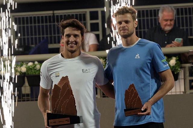 Italy's Luciano Darderi (L) poses with the trophy after winning the ATP Santiago Open men's singles tennis final match against Germany's Yannick Hanfmann (R) at the Club San Carlos de Apoquindo in Santiago on March 1, 2026. (Photo by Rodrigo ARANGUA / AFP)