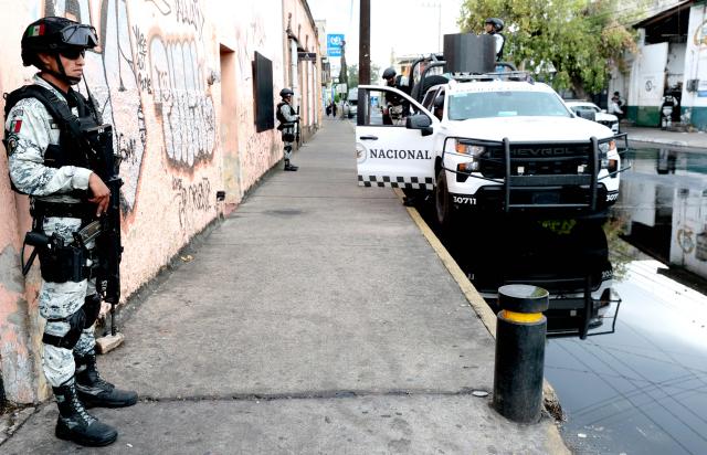 Members of the National Guard guard the perimeter of the La Paz funeral home in Guadalajara, Jalisco state, Mexico, on March 1, 2026. Mexican soldiers watched over a funeral home in the city of Guadalajara (west) on Sunday, where the body of drug trafficker Nemesio "El Mencho" Oseguera, who died on February 22 during a military operation, was being held for a wake. The remains of the leader of the feared Jalisco New Generation Cartel (CJNG) remained inside the premises awaiting burial on Monday, a federal source told several media outlets gathered outside the building. (Photo by ULISES RUIZ / AFP)