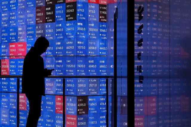 A man stands in front of an electronic quotation board displaying the Nikkei 225 stock prices on the Tokyo Stock Exchange in Tokyo on March 2, 2026. Asian stocks dropped in early trade March 2 on the back of fears for the global economy following US-Israeli attacks on Iran over the weekend. (Photo by Kazuhiro NOGI / AFP)