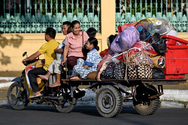 A family rides on a motor-cart travelling along a street in Phnom Penh on March 2, 2026. (Photo by TANG CHHIN Sothy / AFP)