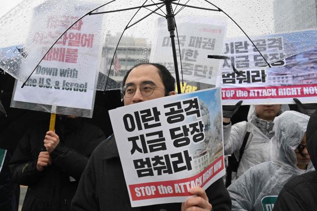 Protesters hold placards reading "Stop the attack right now!" during a demonstration to condemn the US and Israeli attacks on Iran in front of the US embassy in Seoul on March 2, 2026. (Photo by Jung Yeon-je / AFP)