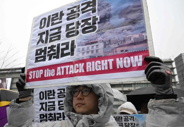Protesters hold placards reading "Stop the attack right now!" during a demonstration to condemn the US and Israeli attacks on Iran in front of the US embassy in Seoul on March 2, 2026. (Photo by Jung Yeon-je / AFP)
