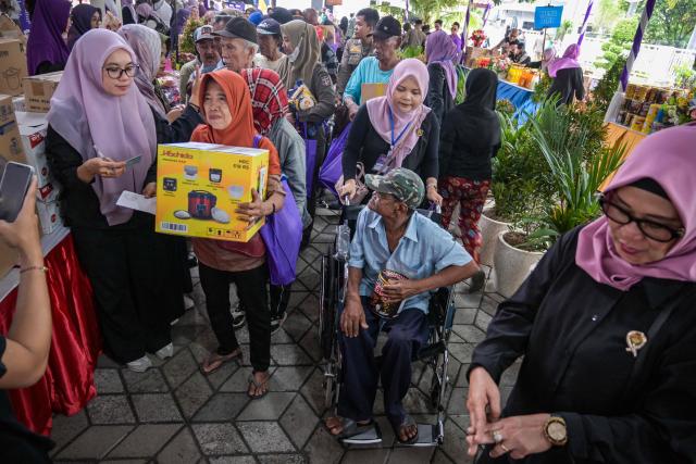People receive free items such as clothing, staple foods and household items provided by the Women's Organization Association (GOW) and the local government during an annual social action event during Ramadan in Surabaya on March 2, 2026. (Photo by JUNI KRISWANTO / AFP)