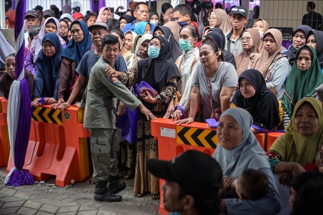 People queue to receive free items such as clothing, staple foods and household items provided by the Women's Organization Association (GOW) and the local government during an annual social action event during Ramadan in Surabaya on March 2, 2026. (Photo by JUNI KRISWANTO / AFP)