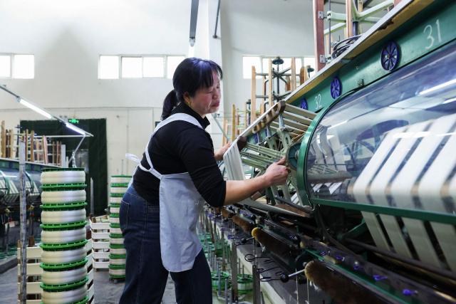 An employee works at a silk factory in Chongqing's Qianjiang district, southwestern China on March 1, 2026. (Photo by CN-STR / AFP) / China OUT