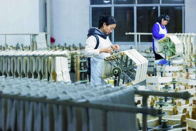 Employees work at a silk factory in Chongqing's Qianjiang district, southwestern China on March 1, 2026. (Photo by CN-STR / AFP) / China OUT