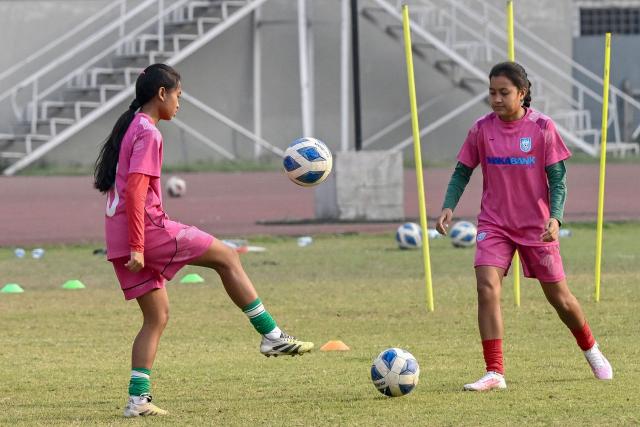 This photograph taken on February 21, 2026 shows Bangladesh women's junior football team taking part in a training session at the National Stadium in Dhaka. Bangladesh's national football team face daunting odds at their first-ever Women's Asian Cup, but have already scored a major victory by qualifying. In the South Asian nation of 170 million, social stigma, family expectations, poverty and religious hardliners have long relegated women and girls to sports sidelines. (Photo by Munir UZ ZAMAN / AFP) / To go with 'FBL-ASIA-2026-WOMEN-BAN' FOCUS