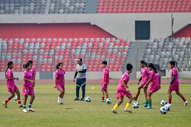 This photograph taken on February 21, 2026 shows Bangladesh women's junior football team taking part in a training session at the National Stadium in Dhaka. Bangladesh's national football team face daunting odds at their first-ever Women's Asian Cup, but have already scored a major victory by qualifying. In the South Asian nation of 170 million, social stigma, family expectations, poverty and religious hardliners have long relegated women and girls to sports sidelines. (Photo by Munir UZ ZAMAN / AFP) / To go with 'FBL-ASIA-2026-WOMEN-BAN' FOCUS