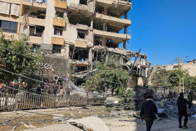 People walk past a building damaged in an Israeli airstrike in the southern suburb of Haret Hreik of Beirut the on March 2, 2026. Israel bombarded Lebanon on March 2, expanding conflict across the region after the massive Israel-US attack on Iran that President Donald Trump launched to topple Tehran's ruling clerics. (Photo by AFP)