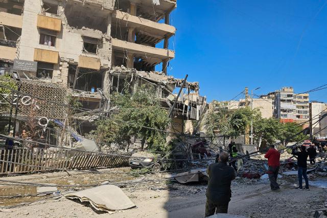 TOPSHOT - People look at a building damaged in an Israeli airstrike in the southern suburb of Haret Hreik of Beirut the on March 2, 2026. Israel bombarded Lebanon on March 2, expanding conflict across the region after the massive Israel-US attack on Iran that President Donald Trump launched to topple Tehran's ruling clerics. (Photo by AFP)