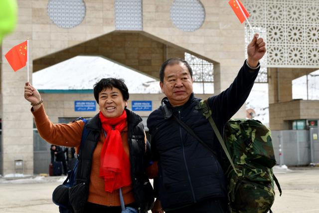 Chinese nationals wave their national flags as they arrive in northeastern Turkey after passing through the Razi-Kapikoy border crossing with Iran in Van, on March 2, 2026 as Turkey and Iran have mutually suspended day-trip crossings at their border, Turkey's trade minister said as Israeli-US strikes continued to pound the Islamic Republic. (Photo by Ali IHSAN OZTURK / AFP)