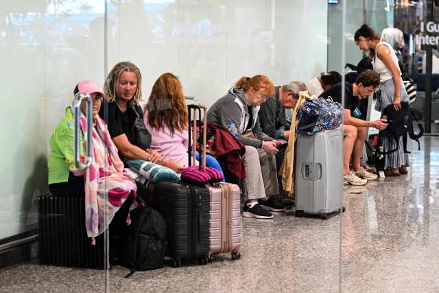 Passengers wait amid flights disruptions as a result of the Israeli-US strikes on Iran, at Ngurah Rai International Airport on Indonesia's resort island of Bali, on March 2, 2026. (Photo by SONNY TUMBELAKA / AFP)
