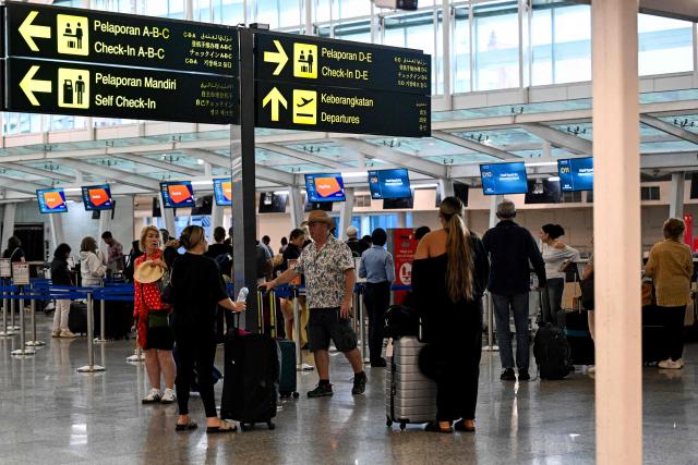 Passengers wait amid flights disruptions as a result of the Israeli-US strikes on Iran, at Ngurah Rai International Airport on Indonesia's resort island of Bali, on March 2, 2026. (Photo by SONNY TUMBELAKA / AFP)