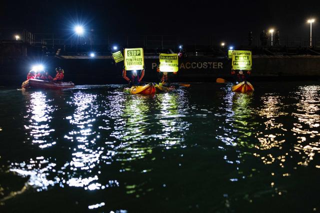 Greenpeace activists hold banners as they take part in an operation to block the cargo ship Mikhail Dudin in Dunkirk, northern France on March 2, 2026. Greenpeace blocked a cargo ship in a lock at the port of Dunkirk (North) to prevent it from unloading its cargo, which the environmental NGO suspects is uranium from Russia intended for the French nuclear sector. The blocking of the cargo ship Mikhail Dudin, which began at 4:10 a.m. and was still underway at 8:00 a.m., was also confirmed by the police, who are also on site. (Photo by Sameer Al-DOUMY / AFP)