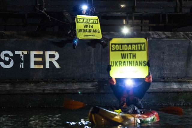 Greenpeace activists hold banners reading "Solidarity with Ukrainians" as they take part in an operation to block the cargo ship Mikhail Dudin in Dunkirk, northern France on March 2, 2026. Greenpeace blocked a cargo ship in a lock at the port of Dunkirk (North) to prevent it from unloading its cargo, which the environmental NGO suspects is uranium from Russia intended for the French nuclear sector. The blocking of the cargo ship Mikhail Dudin, which began at 4:10 a.m. and was still underway at 8:00 a.m., was also confirmed by the police, who are also on site. (Photo by Sameer Al-DOUMY / AFP)