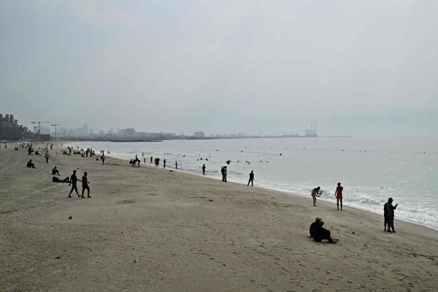 People relax on the Ajman Beach, as the conflict which began on Feruary 28, with the assassination of Iran's supreme leader by the US and Israel continues, in Dubai on March 2, 2026. The United States and Israel launched strikes against Iran on February 28, with the killing of Iran's supreme leader and the Islamic republic retaliated with barrages of missiles at Gulf states and Israel. (Photo by Giuseppe CACACE / AFP)