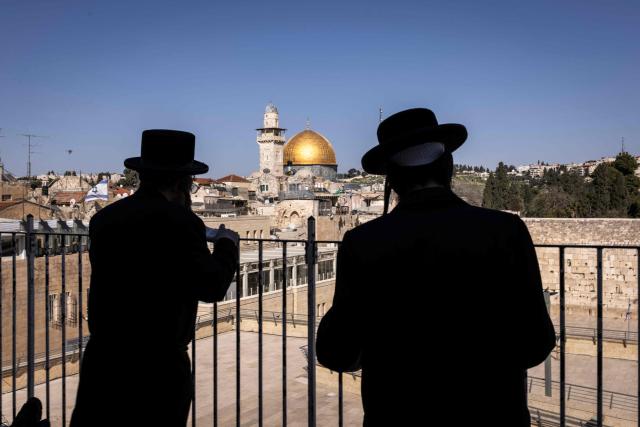 Jewsih ultra-Orthodox men pray outside the closed Western Wall, as they face Islam's Dome of the Rock, in the Old city of Jerusalem on March 2, 2026. The United States and Israel launched strikes against Iran on February 28, with the killing of Iran's supreme leader and the Islamic republic retaliated with barrages of missiles at Gulf states and Israel. (Photo by JOHN WESSELS / AFP)