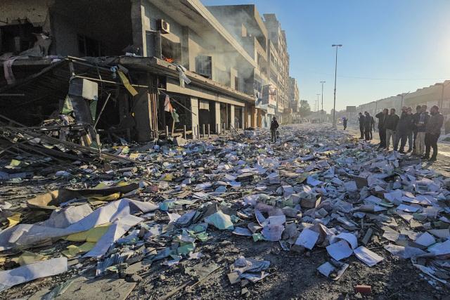 People look at the damage at the site of an Israeli airstrike that targeted the offices of Al-Qard al-Hassan, a Hezbollah-linked financial institution, in the southern coastal Lebanese city of Tyre on March 2, 2026. Israel bombarded Lebanon on March 2, expanding the conflict across the region after the massive Israel-US attack on Iran that the US president launched to topple Tehran's ruling clerics, and killing their supreme leader o February 28. (Photo by KAWNAT HAJU / AFP)