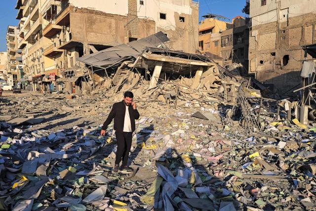 A man makes his way through debris at the site of an Israeli airstrike that targeted the offices of Al-Qard al-Hassan, a Hezbollah-linked financial institution, in the southern coastal Lebanese city of Tyre on March 2, 2026. Israel bombarded Lebanon on March 2, expanding the conflict across the region after the massive Israel-US attack on Iran that the US president launched to topple Tehran's ruling clerics, and killing their supreme leader o February 28. (Photo by KAWNAT HAJU / AFP)