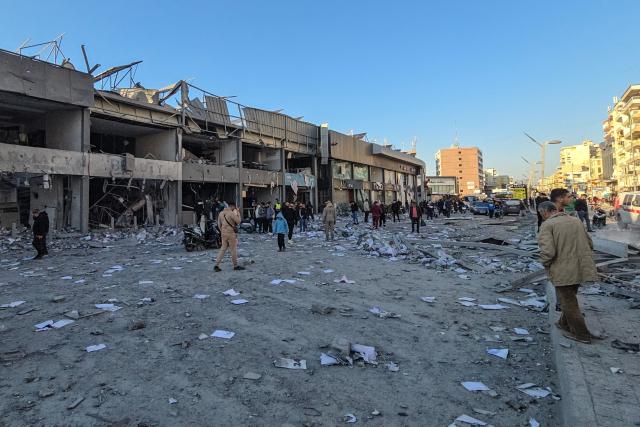 People gather at the site of an Israeli airstrike that targeted the offices of Al-Qard al-Hassan, a Hezbollah-linked financial institution, in the southern coastal Lebanese city of Tyre on March 2, 2026. Israel bombarded Lebanon on March 2, expanding the conflict across the region after the massive Israel-US attack on Iran that the US president launched to topple Tehran's ruling clerics, and killing their supreme leader o February 28. (Photo by KAWNAT HAJU / AFP)