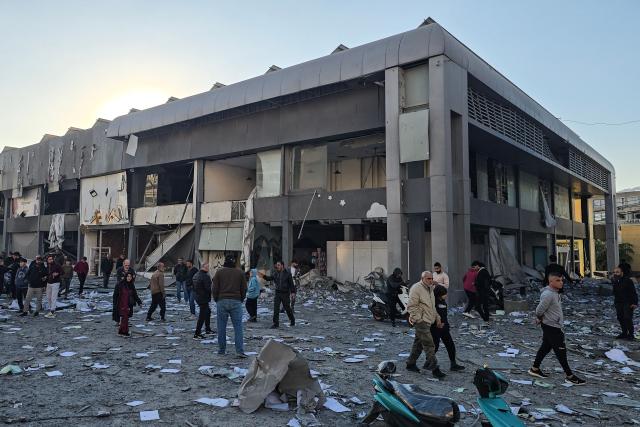 People gather at the site of an Israeli airstrike that targeted the offices of Al-Qard al-Hassan, a Hezbollah-linked financial institution, in the southern coastal Lebanese city of Tyre on March 2, 2026. Israel bombarded Lebanon on March 2, expanding the conflict across the region after the massive Israel-US attack on Iran that the US president launched to topple Tehran's ruling clerics, and killing their supreme leader o February 28. (Photo by KAWNAT HAJU / AFP)