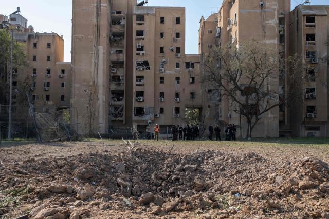 Members of the Israeli security forces stand next to a crater at the scene of an Iranian missile strike in Beersheva on March 2, 2026. The United States and Israel launched strikes against Iran on February 28, killing Iran's supreme leader and top military leaders, prompting authorities to retaliate with strikes on Israel and across the Gulf. (Photo by Maya Levin / AFP)