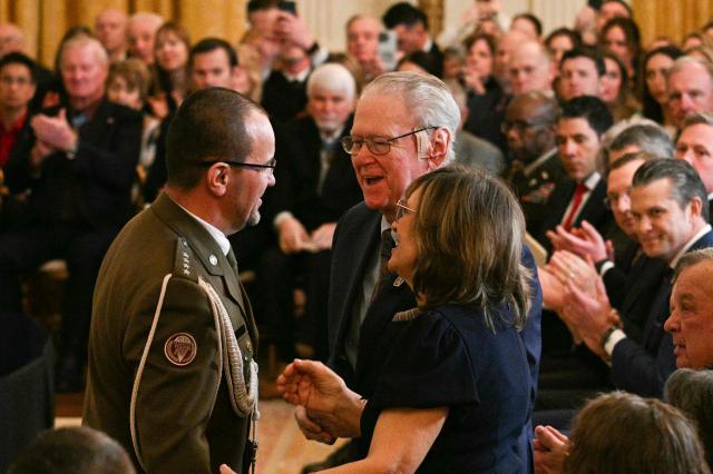 Polish Army Captain Karol Cierpica, who was saved by Army Staff Sgt. Michael Ollis in Afghanistan, greets the parents of Ollis as he is recognized by US President Donald Trump during a Medal of Honor ceremony in the East Room of the White House on March 2, 2026, in Washington, DC. President Trump awarded the Medal of Honor to retired Army Command Sgt. Major Terry P. Richardson, who served in the Vietnam War, posthumously to Army Master Sgt. Roderick W. Edmonds, who served in World War II, and posthumously to Staff Sgt. Michael Ollis, who died in combat in Afghanistan in 2013. (Photo by Jim WATSON / AFP)