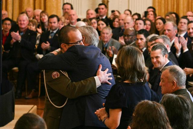 Polish Army Captain Karol Cierpica, who was saved by Army Staff Sgt. Michael Ollis in Afghanistan, embraces the father of Ollis as he is recognized by US President Donald Trump during a Medal of Honor ceremony in the East Room of the White House on March 2, 2026, in Washington, DC. President Trump awarded the Medal of Honor to retired Army Command Sgt. Major Terry P. Richardson, who served in the Vietnam War, posthumously to Army Master Sgt. Roderick W. Edmonds, who served in World War II, and posthumously to Staff Sgt. Michael Ollis, who died in combat in Afghanistan in 2013. (Photo by Jim WATSON / AFP)