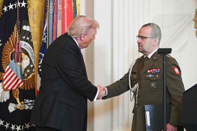 US President Donald Trump looks shakes hands with Polish Army Captain Karol Cierpica, who was saved by Army Staff Sgt. Michael Ollis in Afghanistan, during a Medal of Honor ceremony in the East Room of the White House on March 2, 2026, in Washington, DC. President Trump awarded the Medal of Honor to retired Army Command Sgt. Major Terry P. Richardson, who served in the Vietnam War, posthumously to Army Master Sgt. Roderick W. Edmonds, who served in World War II, and posthumously to Staff Sgt. Michael Ollis, who died in combat in Afghanistan in 2013. (Photo by SAUL LOEB / AFP)