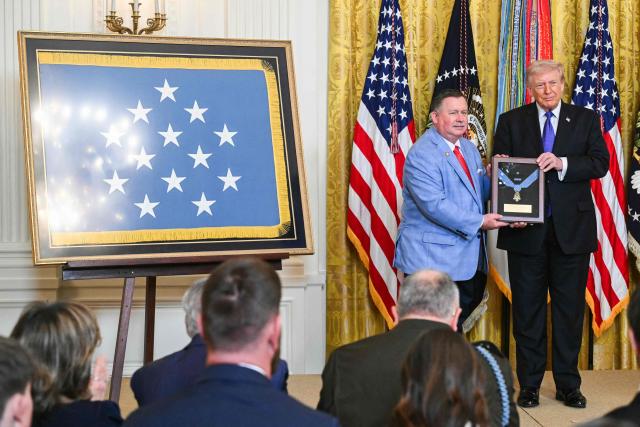 Chris Edmonds (L), son of Army Master Sgt. Roderick W. Edmonds, accepts the Medal of Honor for his late father from US President Donald Trump during a Medal of Honor ceremony in the East Room of the White House on March 2, 2026, in Washington, DC. President Trump awarded the Medal of Honor to retired Army Command Sgt. Major Terry P. Richardson, who served in the Vietnam War, posthumously to Army Master Sgt. Roderick W. Edmonds, who served in World War II, and posthumously to Staff Sgt. Michael Ollis, who died in combat in Afghanistan in 2013. (Photo by SAUL LOEB / AFP)