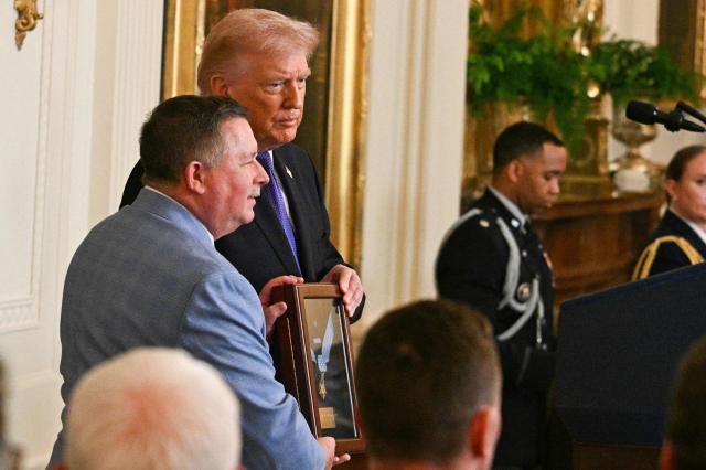 Chris Edmonds (L), son of Army Master Sgt. Roderick W. Edmonds, accepts the Medal of Honor for his late father from US President Donald Trump during a Medal of Honor ceremony in the East Room of the White House on March 2, 2026, in Washington, DC. President Trump awarded the Medal of Honor to retired Army Command Sgt. Major Terry P. Richardson, who served in the Vietnam War, posthumously to Army Master Sgt. Roderick W. Edmonds, who served in World War II, and posthumously to Staff Sgt. Michael Ollis, who died in combat in Afghanistan in 2013. (Photo by Jim WATSON / AFP)