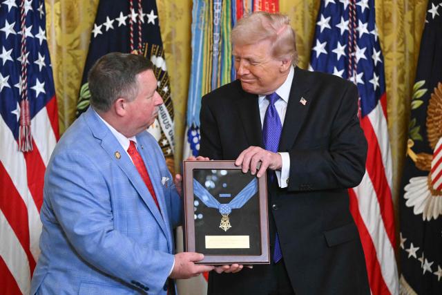 Chris Edmonds (L), son of Army Master Sgt. Roderick W. Edmonds, accepts the Medal of Honor for his late father from US President Donald Trump during a Medal of Honor ceremony in the East Room of the White House on March 2, 2026, in Washington, DC. President Trump awarded the Medal of Honor to retired Army Command Sgt. Major Terry P. Richardson, who served in the Vietnam War, posthumously to Army Master Sgt. Roderick W. Edmonds, who served in World War II, and posthumously to Staff Sgt. Michael Ollis, who died in combat in Afghanistan in 2013. (Photo by SAUL LOEB / AFP)