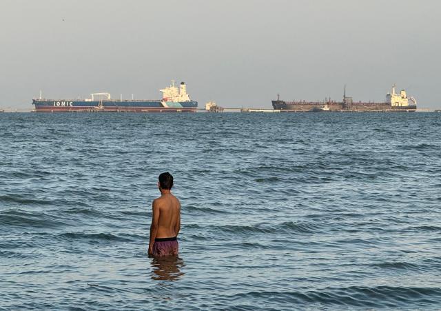 A man enters the water in front of oil tankers docked at Maracaibo Lake in Maracaibo, Venezuela, on March 1, 2026. Venezuela was once a major crude supplier to the US, and has the world's largest proven reserves with more than 303 billion barrels, according to global oil cartel OPEC. (Photo by Margioni BERMÚDEZ / AFP)