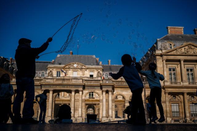 Children play with soap bubbles blown by a street entertainer on a sunny day in front of France’s Council of State in central Paris on March 2, 2026. (Photo by Dimitar DILKOFF / AFP)
