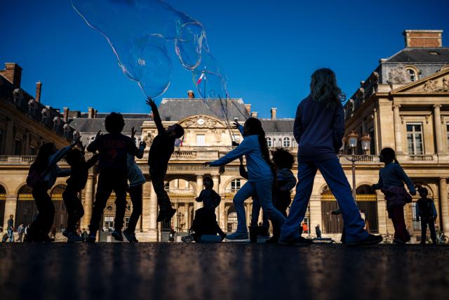 Children play with soap bubbles blown by a street entertainer on a sunny day in front of France’s Council of State in central Paris on March 2, 2026. (Photo by Dimitar DILKOFF / AFP)