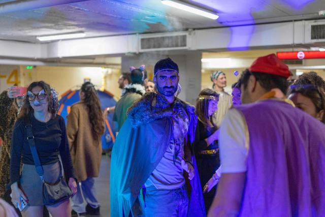 Israelis dressed in costumes gather in a parking lot used as a shelter to celebrate the carnival-like Purim holiday in Tel-Aviv on March 2, 2026. The United States and Israel launched strikes against Iran on February 28, killing Iran's supreme leader and top military leaders, prompting authorities to retaliate with strikes on Israel and across the Gulf. (Photo by Ilia YEFIMOVICH / AFP)