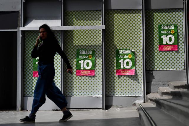 A woman walks past electoral campaign posters of the Colombian Senate candidate for the Green Alliance, Angelica Lozano, in Bogota on March 2, 2026. Colombia will hold legislative elections on March 8, 2026, and presidential election on May 31. (Photo by Pablo VERA / AFP)