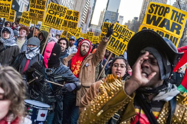 A man flashes the "victory sign" as others hold placards as they rally during a protest against US military action in Iran in New York City, on March 2, 2026. The United States hit hundreds of targets across Iran, and Israel expanded its bombing to Lebanon on March 2 as President Donald Trump vowed to avenge the first US deaths in the war he launched to topple Tehran's ruling clerics. Iranian forces fired missiles and drones across the Middle East, killing people in Israel and the United Arab Emirates, in retaliation for the conflict that began February 28 with the death of Iran's supreme leader, Ayatollah Ali Khamenei. (Photo by Ryan MURPHY / AFP)