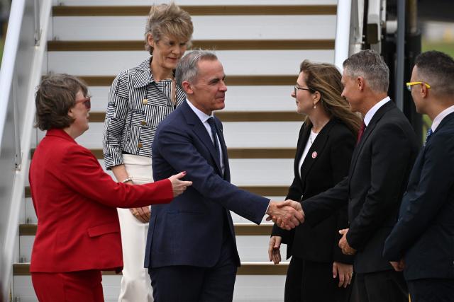 Canada's Prime Minister Mark Carney and his wife Diana Fox Carney (top) are welcomed by officials upon their arrival at Sydney Airport on March 3, 2026. (Photo by Saeed KHAN / AFP)